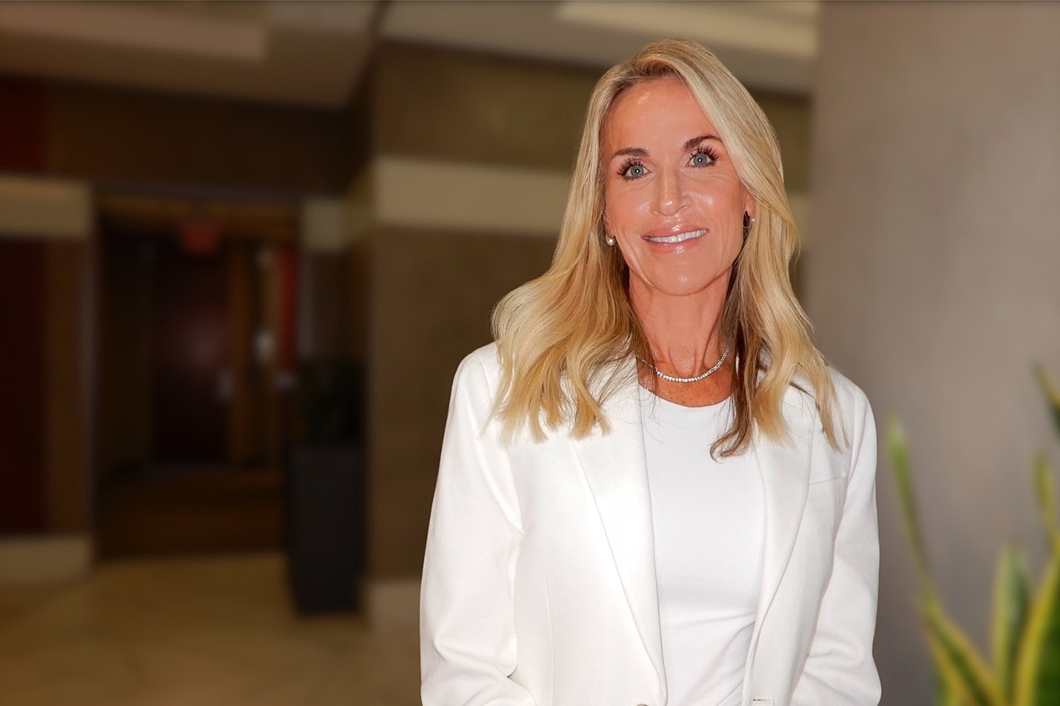 Smiling woman in a white outfit, indoor setting.