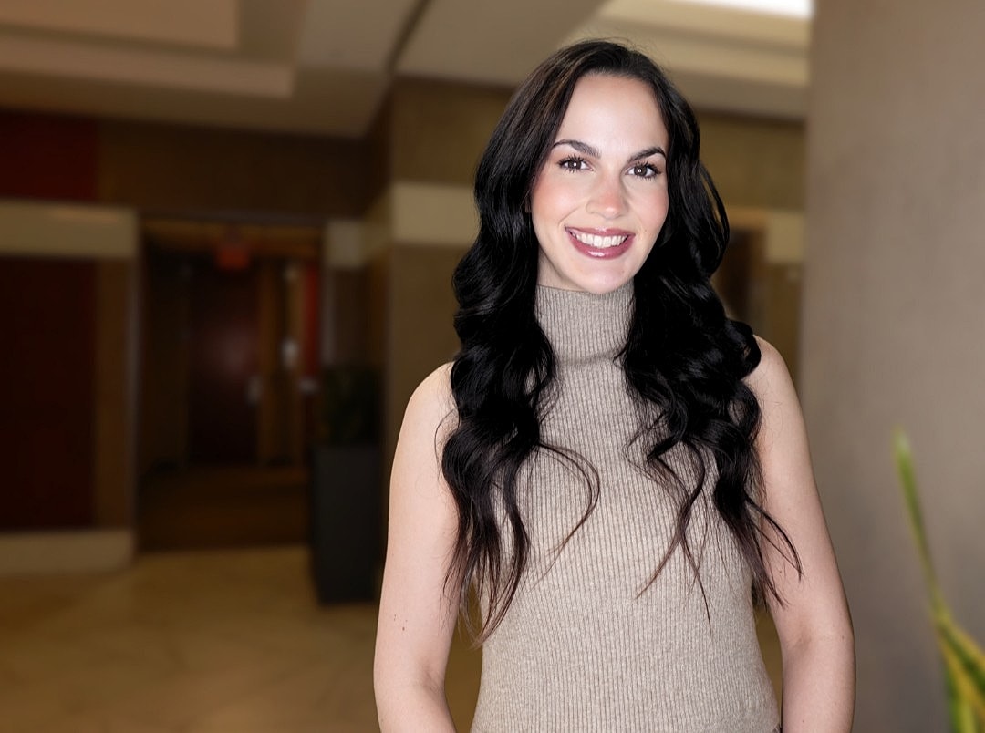 Smiling woman in a stylish sweater, indoor setting.